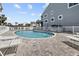 A community pool with lounge chairs, surrounded by white fencing and lush greenery at 911 Harbour House Dr, Indian Rocks Beach, FL 33785