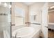 Large soaking tub with tile surround and mosaic accents under a bright window in bathroom at 11109 Great Neck Rd, Riverview, FL 33578
