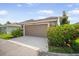 Attached garage with manicured landscaping, an automatic door, and an outdoor light fixture at 11109 Great Neck Rd, Riverview, FL 33578