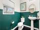 Stylish half-bathroom with green walls, pedestal sink, decorative mirror, and tiled floors at 13110 Shumard Way, Riverview, FL 33579