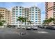 Exterior view of white condos with multiple balconies and lush landscaping in a parking area at 1350 Gulf Blvd # 502, Clearwater Beach, FL 33767