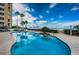Scenic pool area with lounge chairs, umbrellas, palm trees, and beach access under a clear blue sky at 1350 Gulf Blvd # 502, Clearwater Beach, FL 33767