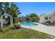 Backyard featuring a refreshing in-ground pool, landscaped with mature trees and comfortable lounge furniture at 1508 Eden Isle Ne Blvd, St Petersburg, FL 33704
