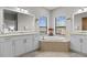 This bathroom has an oval soaking tub with two vanities and mirrors, with natural light and plants at 1537 Ember Ln, Tarpon Springs, FL 34689
