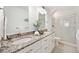 Bathroom boasts double vanity with granite countertops, white cabinetry, and a glass-enclosed shower at 17920 Gulf Blvd # 2004, Redington Shores, FL 33708