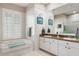 Well-lit bathroom featuring dual sinks, a bathtub, and tiled floors for a luxurious feel at 18241 Autumn Lake Blvd, Hudson, FL 34667