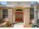 Inviting entryway featuring a vibrant red double-door and charming brick facade at 18241 Autumn Lake Blvd, Hudson, FL 34667