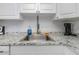 This kitchen features a stainless steel sink with granite countertops, white cabinets, and mosaic backsplash at 1900 68Th N St # 110, St Petersburg, FL 33710