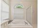 Bathroom featuring a large soaking tub, walk-in shower, and arched window for natural light at 2159 Warwick Dr, Oldsmar, FL 34677