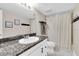 Well-lit bathroom featuring a white vanity with a granite countertop, a toilet and a shower with curtain at 2647 Barksdale Ct, Clearwater, FL 33761