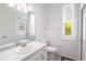 Bathroom with light blue tile, single sink vanity, white toilet, window and access to outside at 3027 Key Harbor Dr, Safety Harbor, FL 34695