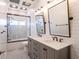 Beautiful bathroom featuring double sinks, gray cabinetry, marble counters, subway tile and stand-up shower at 3027 Key Harbor Dr, Safety Harbor, FL 34695