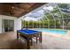 Inviting screened-in pool area with travertine tile and outdoor game space at 3027 Key Harbor Dr, Safety Harbor, FL 34695