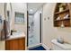 Modern bathroom with a wooden vanity, decorative mirror, and a walk-in shower with blue pebble flooring at 315 Medallion Blvd # E, Madeira Beach, FL 33708