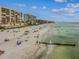 Serene beach view with calm, clear turquoise water, a sandy beach, and beachfront condominiums at 315 Medallion Blvd # E, Madeira Beach, FL 33708