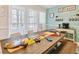Cheerful dining area with a wooden table displaying beach tennis equipment, a coffee bar, and sheer curtains at 315 Medallion Blvd # E, Madeira Beach, FL 33708