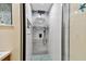 Close-up of a modern shower featuring white and gray tile, a rainfall showerhead, and frameless glass doors at 315 Medallion Blvd # E, Madeira Beach, FL 33708