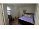 Cozy bedroom with a floral-patterned bedspread, window and door with natural light, and wood laminate flooring at 3527 Greenglen Cir, Palm Harbor, FL 34684
