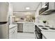 Modern kitchen with white cabinets, stainless steel appliances, and an open view to the living area at 36750 Us 19 N # 20211, Palm Harbor, FL 34684