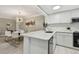 Open concept kitchen with a stylish chandelier, white cabinets, stainless steel appliances, and breakfast nook at 36750 Us 19 N # 20211, Palm Harbor, FL 34684