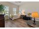 Bright bedroom with wood floors, white furniture, and lots of natural light from the two windows at 4839 Pointe O Woods Dr, Wesley Chapel, FL 33543