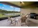 Inviting covered patio overlooking a serene lake, complete with outdoor furniture and a grill at 4839 Pointe O Woods Dr, Wesley Chapel, FL 33543