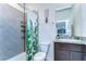 Well-lit bathroom featuring tiled shower, modern vanity with granite countertop, and tropical-themed shower curtain at 5325 Thistle Field Ct, Wesley Chapel, FL 33545