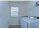 Bright laundry room with a window and modern washer and dryer units at 5325 Thistle Field Ct, Wesley Chapel, FL 33545