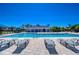 Community swimming pool with many lounge chairs and shade umbrellas, plus the nearby clubhouse at 5325 Thistle Field Ct, Wesley Chapel, FL 33545