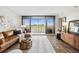 Living room with sliding glass doors to balcony offering stunning city views, leather sofa, and modern decor at 5950 Pelican Bay S Plz # 603, Gulfport, FL 33707