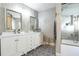 Bathroom with double sink vanity, decorative mirrors, and a tiled shower with built-in shelving at 6311 Bayside Dr, New Port Richey, FL 34652