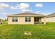 Green backyard featuring a tan house with dark trim and a covered patio visible in the background at 6882 Silverado Ranch Blvd, Zephyrhills, FL 33541