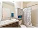 Well-lit bathroom featuring a vanity with a white sink, a storage cabinet, and a shower with a polka dot curtain at 6882 Silverado Ranch Blvd, Zephyrhills, FL 33541