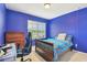 Bright bedroom with a blue accent wall, carpet flooring, a bed, a desk, and a window with backyard views at 6882 Silverado Ranch Blvd, Zephyrhills, FL 33541