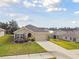 Aerial view of a one-story home showcasing its beige facade, well-kept lawn, and nicely landscaped front yard at 6882 Silverado Ranch Blvd, Zephyrhills, FL 33541