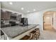 Kitchen features a granite countertop island with seating, black appliances, and tile backsplash at 6882 Silverado Ranch Blvd, Zephyrhills, FL 33541