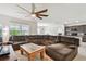 Spacious living room featuring a ceiling fan, large sectional sofa, and open concept to kitchen at 6882 Silverado Ranch Blvd, Zephyrhills, FL 33541