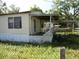 Home with a porch and adjacent carport, surrounded by a chain link fence at 851 Easy St, Brooksville, FL 34601