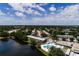 Aerial view of a community with a lake, pool, clubhouse, and greenery under a partly cloudy sky at 8555 112Th St # 209, Seminole, FL 33772