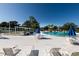 Community pool area with lounge chairs, umbrellas, and a view of lush landscaping under a clear sky at 8555 112Th St # 209, Seminole, FL 33772