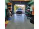 Finished garage with epoxy floor, shelving, and a black car parked in the driveway outside at 10216 Seminole Island Dr, Largo, FL 33773