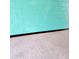 Close-up of a turquoise cinder block garage wall with a black baseboard and speckled epoxy floor at 10216 Seminole Island Dr, Largo, FL 33773