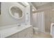 Bathroom with white vanity, round mirror, and walk-in shower with glass doors at 1201 Montrose Pl, Dunedin, FL 34698