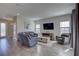 Spacious living room featuring wood-look tile flooring, a large TV, and neutral decor at 12421 Triple Creek Blvd, Riverview, FL 33579