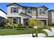 Charming two-story home boasts a well-manicured lawn, complemented by lush tropical landscaping, and a gray front door at 12957 Wildflower Meadow Dr, Riverview, FL 33579