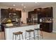 Modern kitchen with dark wood cabinets, stainless steel appliances, granite countertops, and an island with barstool seating at 12957 Wildflower Meadow Dr, Riverview, FL 33579