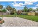 Landscaped backyard featuring a large brick patio, a playset, palm trees, and a wooden fence at 138 17Th N Ave, St Petersburg, FL 33704