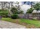 Landscaped backyard with mature trees, grass, wooden fence, trimmed shrubs, and a gray tiled patio area at 1466 Normandy Park Dr # 4, Clearwater, FL 33756