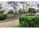 Backyard featuring a wooden fence, trimmed hedges, grass lawn, and mature trees against a cloudy sky at 1466 Normandy Park Dr # 4, Clearwater, FL 33756
