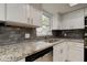 Close-up of updated kitchen with white cabinets, granite countertops, stainless steel sink, and stylish subway tile backsplash at 1466 Normandy Park Dr # 4, Clearwater, FL 33756